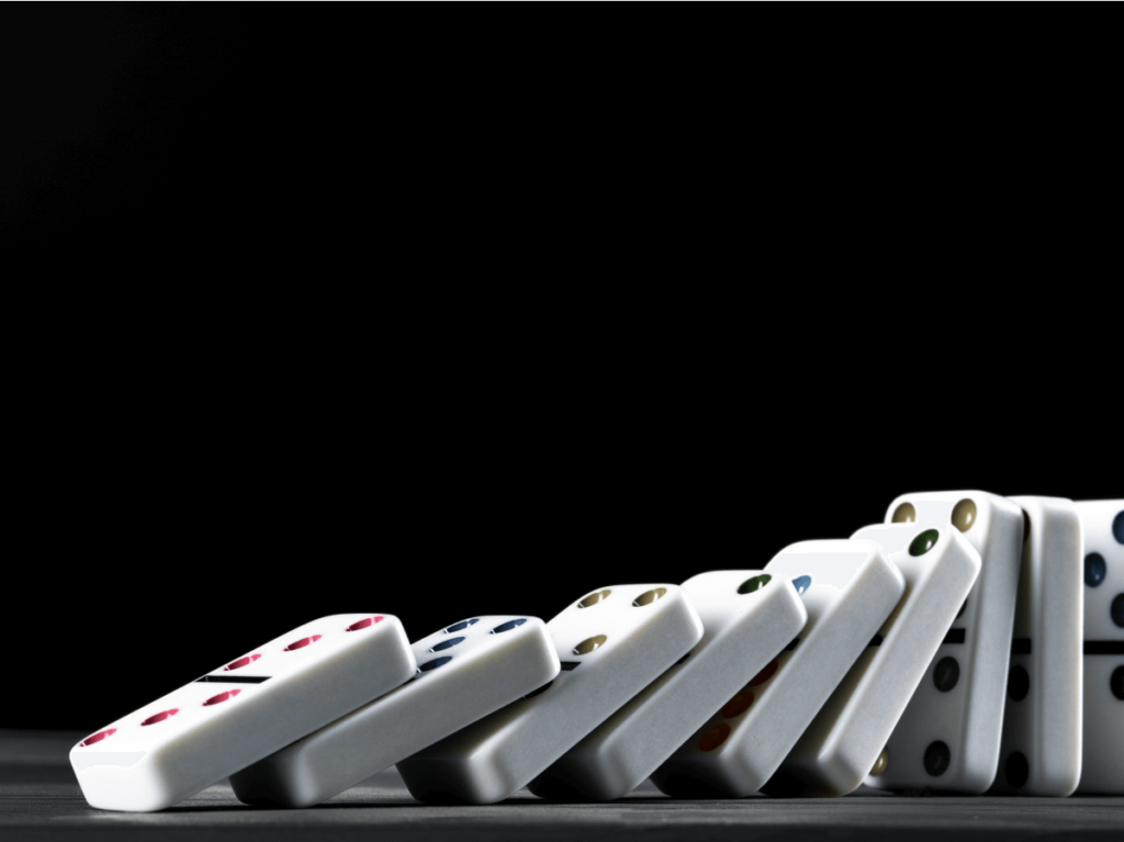 A row of dominoes toppling over against a black background